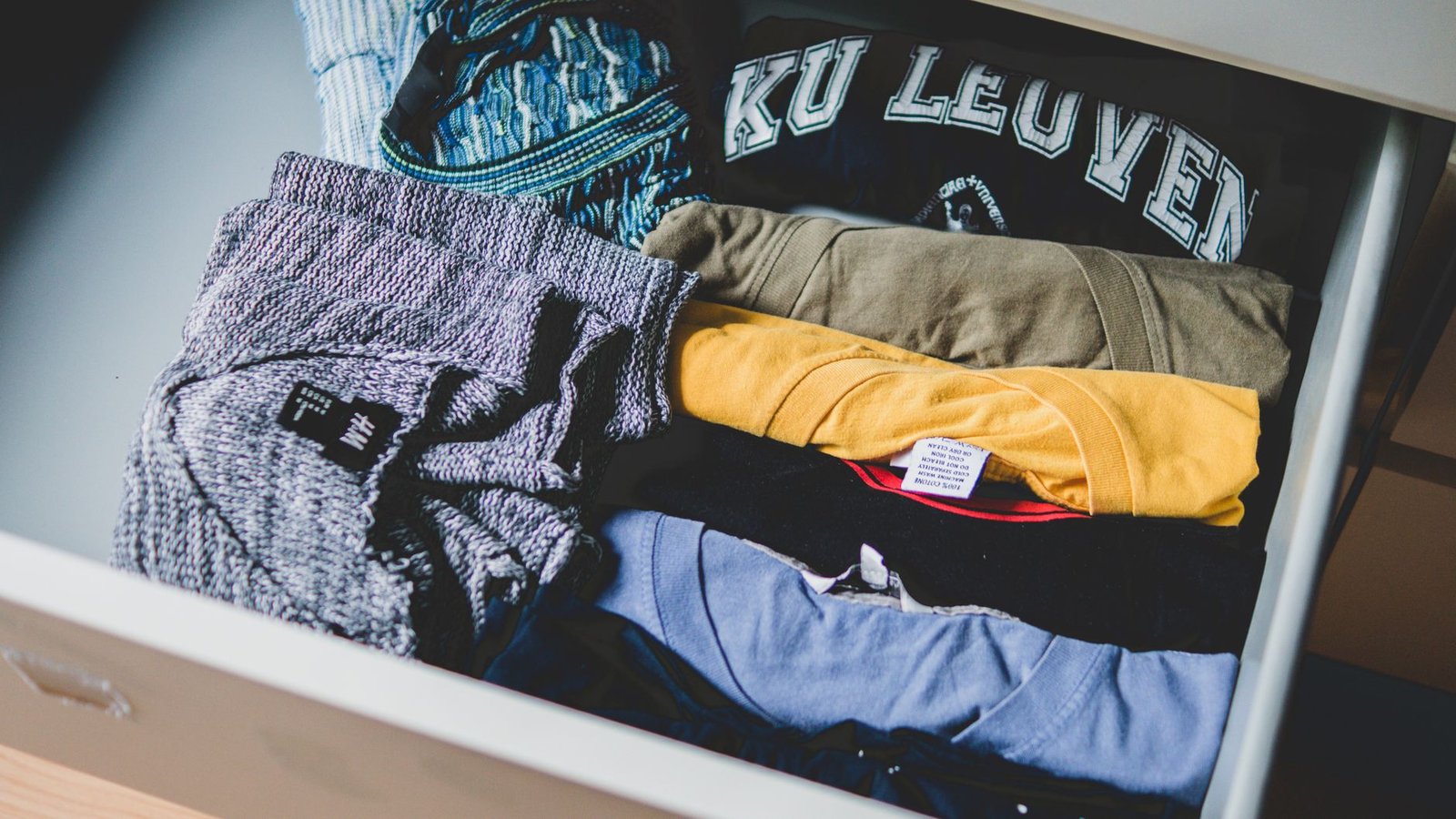 A drawer with six neatly folded pairs of underwear in neutral colors, a fabric measuring tape draped across the top.