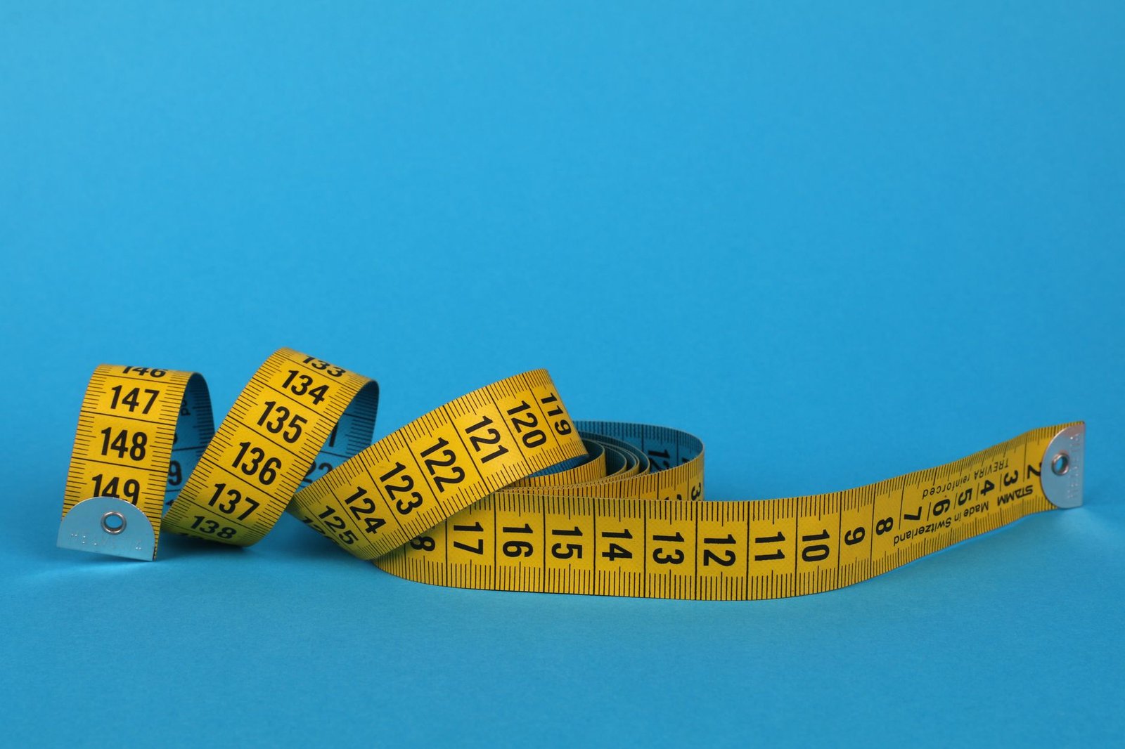 a tailor's tape measure draped over a pair of men's boxer briefs on a wooden surface, with a notebook and pen nearby