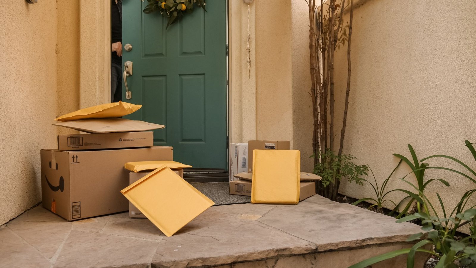 A stack of three unopened men's underwear subscription boxes on a doorstep, one with a torn corner revealing a glimpse of folded fabric.